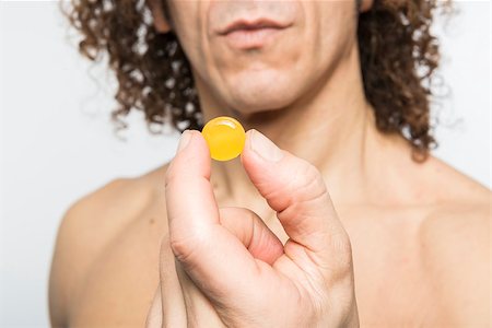 Cropped shot of bare chested mediterranean man holding colourful pill Stock Photo - Budget Royalty-Free & Subscription, Code: 400-07406649