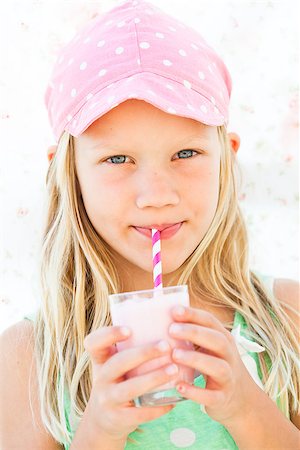 Cute young girl drinking milk fruit smoothie with striped straw from glass held in hands Stock Photo - Budget Royalty-Free & Subscription, Code: 400-07409829