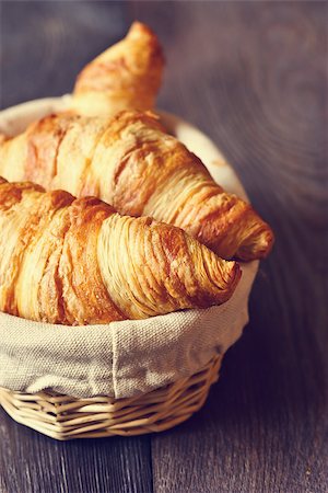 Fresh croissants for breakfast in a basket on a wooden background. Toned photo. Fotografie stock - Microstock e Abbonamento, Codice: 400-07414865