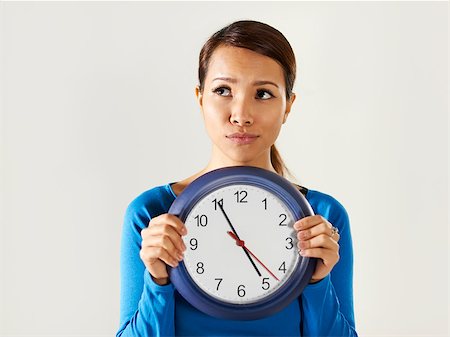 rush hour japanese - portrait of asian business woman holding big blue watch and looking away with worried expression. Copy space Stock Photo - Budget Royalty-Free & Subscription, Code: 400-07417196