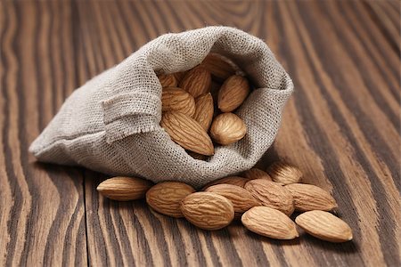 small sack bag full of almonds, on wooden table Foto de stock - Super Valor sin royalties y Suscripción, Código: 400-07417539