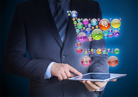 simsearch:400-07446368,k - Businessman in a suit holding a tablet in his hands. Above the screen tablet application icons in the form of trolley Foto de stock - Super Valor sin royalties y Suscripción, Código: 400-07419698