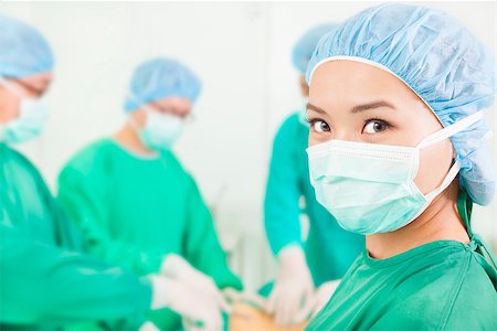 simsearch:400-07412761,k - Woman surgeon working with team in a surgical room Foto de stock - Royalty-Free Super Valor e Assinatura, Número: 400-07412765