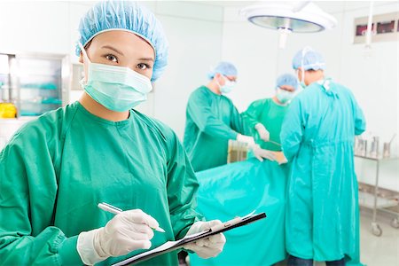 simsearch:400-07412761,k - woman Surgeons writing medical record in operation room Foto de stock - Royalty-Free Super Valor e Assinatura, Número: 400-07412770