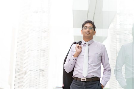 Candid portrait of 30s Asian Indian businessman walking outside office. India male business man, real modern office building as background with natural sunlight. Stock Photo - Budget Royalty-Free & Subscription, Code: 400-07424766