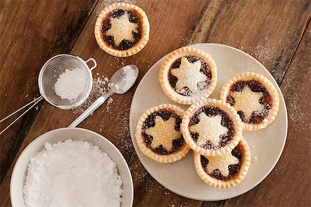 stockarch (artist) - Traditional Christmas fruit mince pies decorated with pastry stars on a kitchen table ready to be sprinkled with powdered icing sugar in a sieve for a delicious seasonal teatime snack, overhead view Foto de stock - Royalty-Free Super Valor e Assinatura, Número: 400-07427316