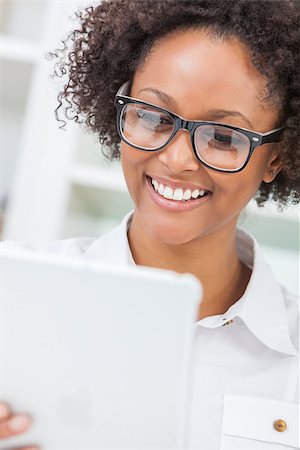 A beautiful happy mixed race African American girl or young woman wearing geek glasses & using a tablet computer in her kitchen Stock Photo - Budget Royalty-Free & Subscription, Code: 400-07423735