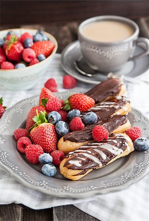 simsearch:400-07621036,k - Chocolate eclairs and fresh berries on plate with cup of coffee on the background Photographie de stock - Aubaine LD & Abonnement, Code: 400-07446415