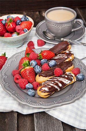 simsearch:400-07621036,k - Chocolate eclairs and fresh berries on plate with cup of coffee on the background Photographie de stock - Aubaine LD & Abonnement, Code: 400-07446416