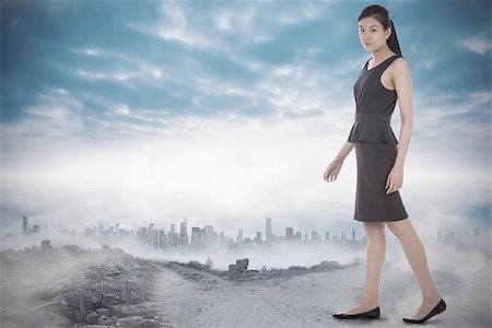 simsearch:400-07446838,k - Asian businesswoman walking against dusty path leading to city under the clouds Photographie de stock - Aubaine LD & Abonnement, Code: 400-07446990