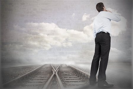simsearch:400-07446838,k - Thinking businessman touching chin against train tracks leading to brick wall with clouds Photographie de stock - Aubaine LD & Abonnement, Code: 400-07447365