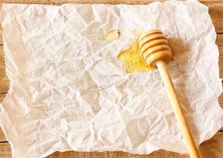 simsearch:400-06640106,k - Wooden honey dipper with honey on a crumpled paper with copy space for text. Stock Photo - Budget Royalty-Free & Subscription, Code: 400-07450534