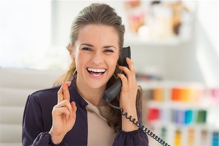 Portrait of happy fashion designer talking phone with crossed fingers Stock Photo - Budget Royalty-Free & Subscription, Code: 400-07450938