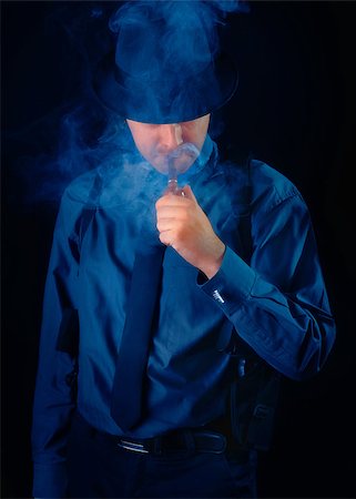 simsearch:400-07464688,k - Man with gun holstered smoking a pipe on a black background Photographie de stock - Aubaine LD & Abonnement, Code: 400-07464686