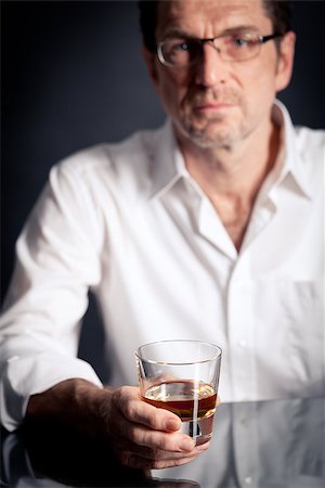 adult man holding an alcoholic drink thoughtful on black background Photographie de stock - Aubaine LD & Abonnement, Code: 400-07464924