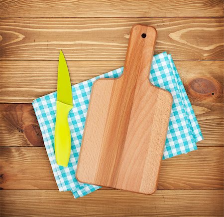 Cutting board and knife over kitchen towel on wooden table background Stock Photo - Budget Royalty-Free & Subscription, Code: 400-07465205