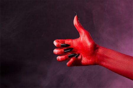 simsearch:400-07209176,k - Red devil hand with black nails showing thumbs up, studio shot on smoky background Stockbilder - Microstock & Abonnement, Bildnummer: 400-07465485