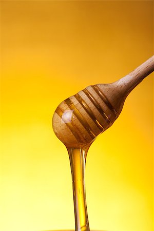 simsearch:400-06640106,k - Wooden drizzler with flowing honey over yellow background Stock Photo - Budget Royalty-Free & Subscription, Code: 400-07465494