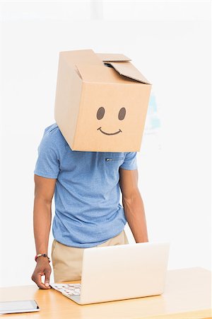 simsearch:6108-05868494,k - Casual young man with happy smiley box over face in front of laptop at office Foto de stock - Super Valor sin royalties y Suscripción, Código: 400-07466564