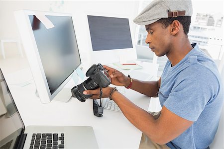 Side view of a male photo editor looking at digital camera in his office Stock Photo - Budget Royalty-Free & Subscription, Code: 400-07466588
