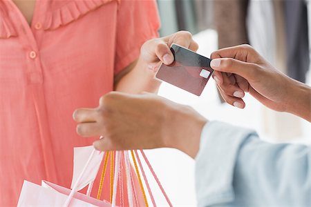 Closeup mid section of female customer receiving shopping bags and credit card from saleswoman in boutique Stock Photo - Budget Royalty-Free & Subscription, Code: 400-07466618