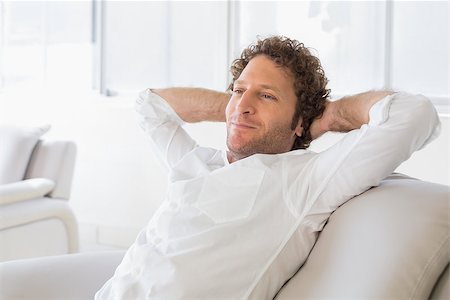 Relaxed well dressed man sitting with hands behind head on sofa in the house Stock Photo - Budget Royalty-Free & Subscription, Code: 400-07466641