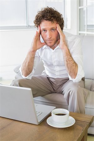 simsearch:400-07274613,k - Portrait of a worried well dressed young man sitting with laptop in the house Stock Photo - Budget Royalty-Free & Subscription, Code: 400-07466658