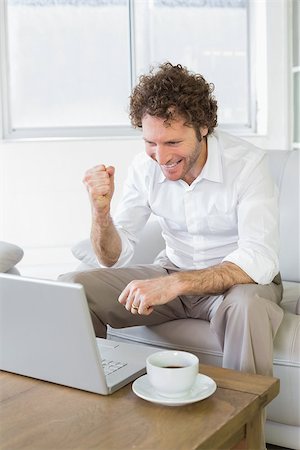 simsearch:400-07274613,k - Happy well dressed relaxed young man looking at laptop on sofa in the house Stock Photo - Budget Royalty-Free & Subscription, Code: 400-07466661