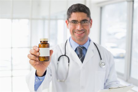 simsearch:400-04130714,k - Portrait of a smiling male doctor holding a bottle of pills in the hospital Photographie de stock - Aubaine LD & Abonnement, Code: 400-07466764