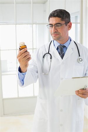 simsearch:400-04130714,k - Male doctor looking at a bottle of pills in the hospital Photographie de stock - Aubaine LD & Abonnement, Code: 400-07466765