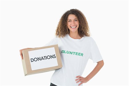 Smiling volunteer holding a box of donations with hand on hip on white background Stockbilder - Microstock & Abonnement, Bildnummer: 400-07467198