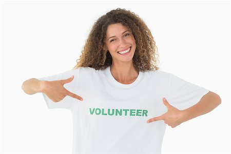 Smiling volunteer pointing to her tshirt looking at camera on white background Stockbilder - Microstock & Abonnement, Bildnummer: 400-07467203