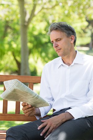 Businessman reading newspaper on bench at the park Stock Photo - Budget Royalty-Free & Subscription, Code: 400-07467405