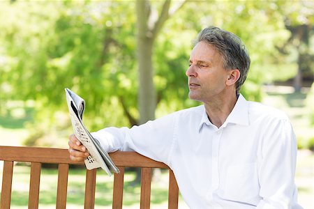 Relaxed businessman reading newspaper in the park Stock Photo - Budget Royalty-Free & Subscription, Code: 400-07467402