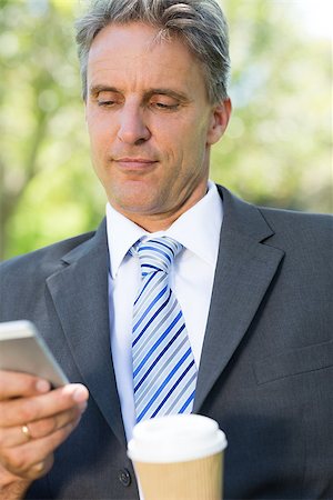 Mature businessman reading text message on cellphone at park Stock Photo - Budget Royalty-Free & Subscription, Code: 400-07467416