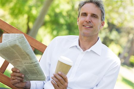 Portrait of businessman holding newspaper and coffee cup in the park Stock Photo - Budget Royalty-Free & Subscription, Code: 400-07467410