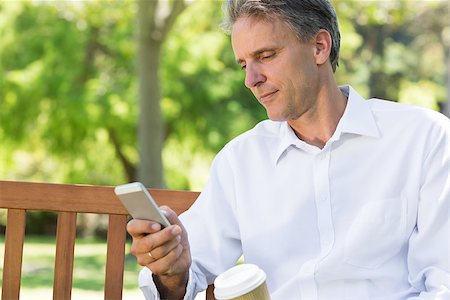 Mature businessman reading text message on mobile phone at park Stock Photo - Budget Royalty-Free & Subscription, Code: 400-07467412