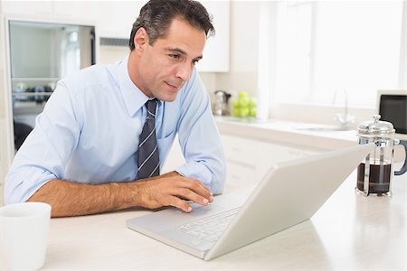 simsearch:400-07274613,k - Concentrated well dressed man using laptop in the kitchen at home Stock Photo - Budget Royalty-Free & Subscription, Code: 400-07467832