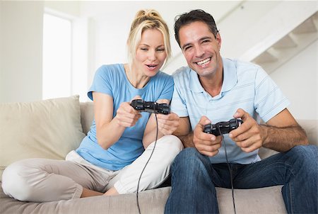 Portrait of a cheerful couple playing video games in the living room at home Photographie de stock - Aubaine LD & Abonnement, Code: 400-07467927