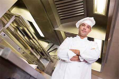 simsearch:400-07468062,k - Portrait of a smiling male cook with arms crossed standing in the kitchen Stockbilder - Microstock & Abonnement, Bildnummer: 400-07468057