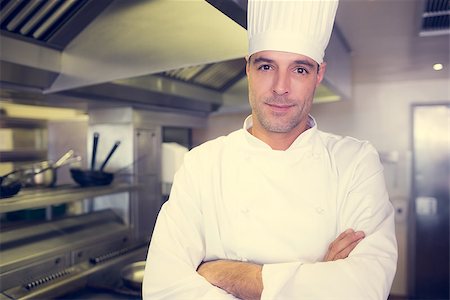 simsearch:400-07468062,k - Portrait of a smiling male cook with arms crossed standing in the kitchen Stockbilder - Microstock & Abonnement, Bildnummer: 400-07468050