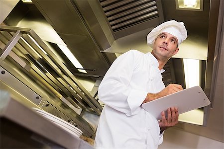 simsearch:400-07468062,k - Low angle view of a serious male cook with clipboard standing in the kitchen Stockbilder - Microstock & Abonnement, Bildnummer: 400-07468064