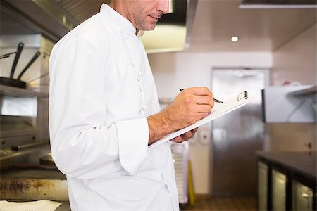 simsearch:400-07468062,k - Side view of a concentrated male cook writing on clipboard in the kitchen Stockbilder - Microstock & Abonnement, Bildnummer: 400-07468066