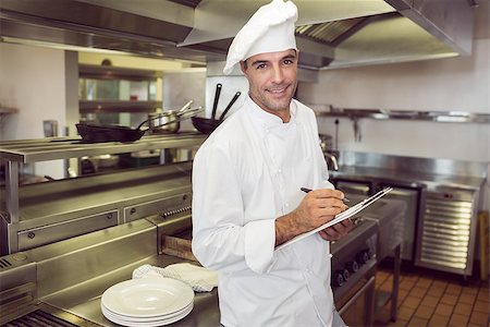 simsearch:400-07468062,k - Portrait of a smiling male cook writing on clipboard in the kitchen Stockbilder - Microstock & Abonnement, Bildnummer: 400-07468069