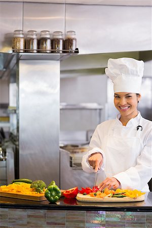 simsearch:400-06105151,k - Portrait of a smiling young female chef cutting vegetables in the kitchen Foto de stock - Super Valor sin royalties y Suscripción, Código: 400-07468159