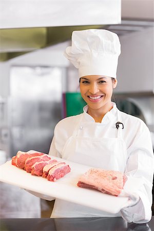 Portrait of a smiling young female chef holding tray of cut meat in the kitchen Stock Photo - Budget Royalty-Free & Subscription, Code: 400-07468184