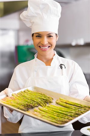 Portrait of a smiling female chef holding tray of fresh asparagus in the kitchen Stock Photo - Budget Royalty-Free & Subscription, Code: 400-07468182