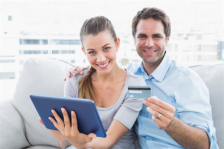 simsearch:400-07474252,k - Happy couple sitting on the couch shopping online with tablet pc at home in the living room Stock Photo - Budget Royalty-Free & Subscription, Code: 400-07474221