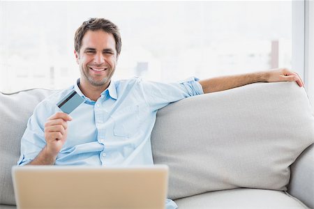 simsearch:400-07474252,k - Happy man using laptop sitting on sofa shopping online at home in the living room Stock Photo - Budget Royalty-Free & Subscription, Code: 400-07474243