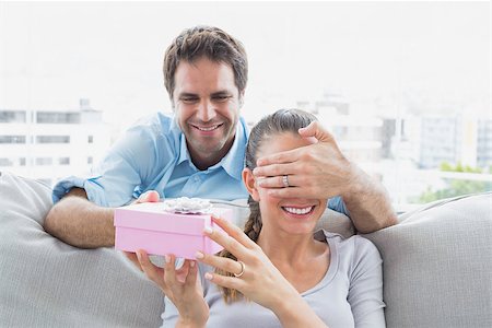 simsearch:6109-07601570,k - Man surprising his girlfriend with a pink gift on the sofa at home in the living room Stockbilder - Microstock & Abonnement, Bildnummer: 400-07474291